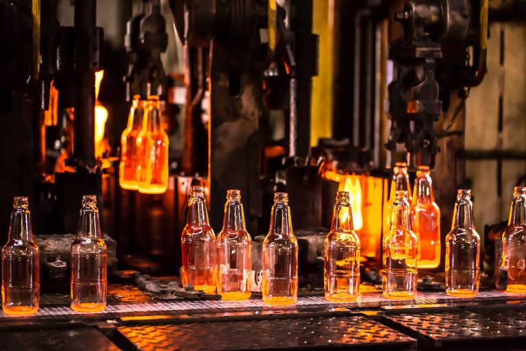 Fábrica de vidrio, producción industrial de envases de vidrio. Tecnología moderna, máquinas robots fabrican productos.Botellas de fiesta para bebidas. Trabajo tecnológico en la fábrica. Ambiente de trabajo con espacio de copia.